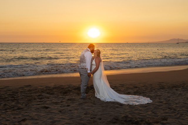 Destination wedding couple kiss on the beach at sunset