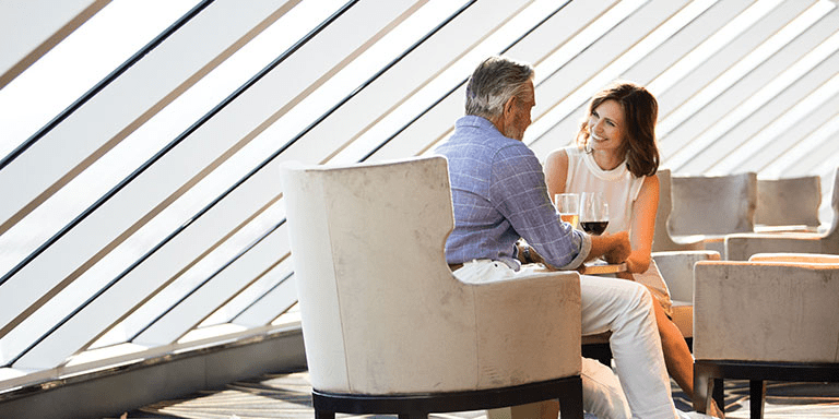A couple drinking wine before dinner on a Regent cruise enjoying the exclusivity. 